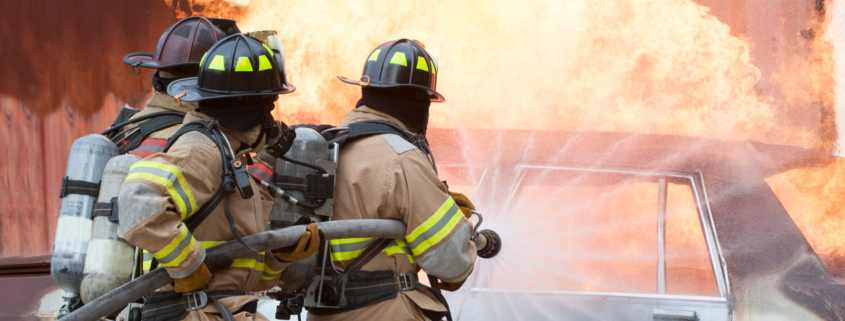 Three firemen extinguishing a car fire.