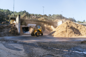 Industrial loader handling wood byproducts at sawmill plant